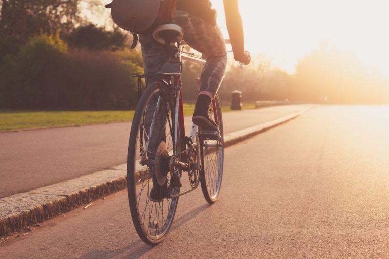 Cyclist riding along a road at sunset